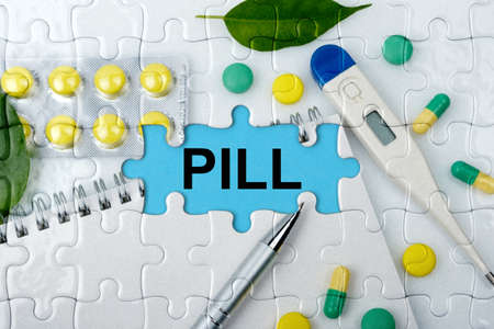 Double exposure. Puzzles with the image of tablets, a notebook, a thermometer and a pen with the inscription -PILL. The concept of medicine.の写真素材