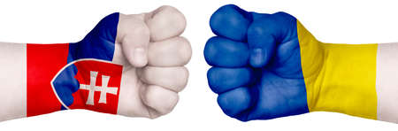 The concept of the struggle of peoples. Two hands are clenched into fists and are located opposite each other. Hands painted in the colors of the flags of the countries. Slovakia vs Ukraineの写真素材