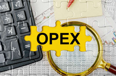 Business concept. Puzzle with a calculator, magnifying glasses and financial documents in the center inscription -OPEXの写真素材