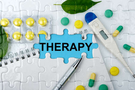 Double exposure. Puzzles with the image of tablets, a notebook, a thermometer and a pen with the inscription -THERAPY. The concept of medicine.の写真素材