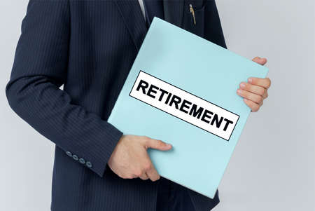 Business concept. A businessman holds a folder with documents, the text on the folder is - RETIREMENTの写真素材