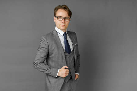 Portrait of a businessman in a suit looking at the camera. Gray background. Business and finance conceptの写真素材