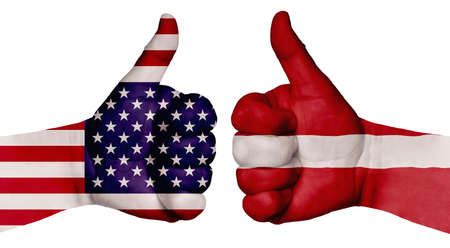 The concept of strengthening the relationship of nations. Two hands are painted with flags of different countries, with a thumb raised up. Latvia and the USAの写真素材