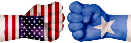 The concept of the struggle of peoples. Two hands are clenched into fists and are located opposite each other. Hands painted in the colors of the flags of the countries. Somalia vs USAの写真素材