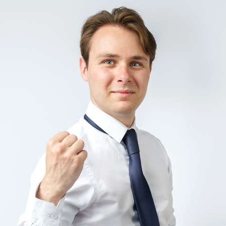 Portrait of a businessman raised his hand clenched into a fist. White background. Business and finance conceptの写真素材