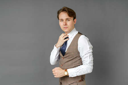 Portrait of a businessman holding his tie with his hand. Gray background. Business and finance conceptの写真素材