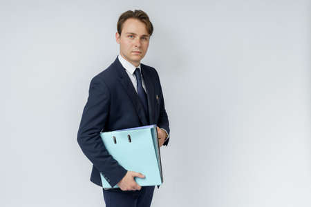 A businessman in a blue suit holds folders on a white background. Business and finance conceptの写真素材