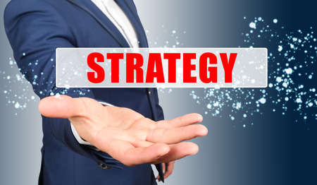 Finance and business concept. A businessman holds his hand, palm up, above the palm the inscription - STRATEGYの写真素材