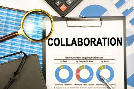 Finance and business concept. The businessman has on his desk graphs with reports, a notebook, a magnifying glass and a document with the inscription - COLLABORATIONの写真素材
