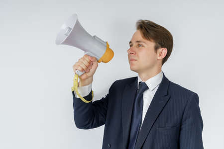 A businessman speaks into a loudspeaker. White background. Business and finance conceptの写真素材