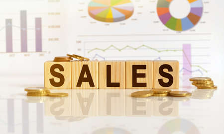 SALES the word on wooden cubes, cubes stand on a reflective surface, in the background is a business diagram. Business and finance conceptの写真素材