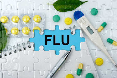 Double exposure. Puzzles with the image of tablets, a notebook, a thermometer and a pen with the inscription -FLU. The concept of medicine.の写真素材