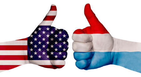 The concept of strengthening the relationship of nations. Two hands are painted with flags of different countries, with a thumb raised up. Luxembourg and the USAの写真素材