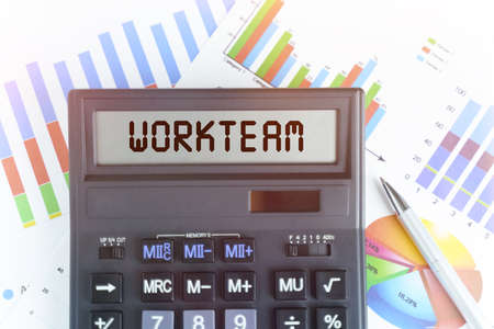 The concept of business and finance. On the table are financial charts and a calculator, on the electronic board of which is written the text - WORKTEAMの写真素材