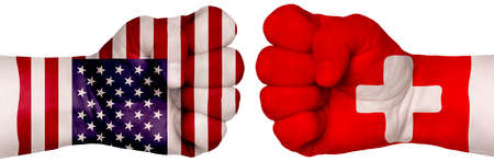 The concept of the struggle of peoples. Two hands are clenched into fists and are located opposite each other. Hands painted in the colors of the flags of the countries. Switzerland vs USAの写真素材