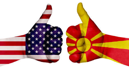The concept of strengthening the relationship of nations. Two hands are painted with flags of different countries, with a thumb raised up. Macedonia and the USAの写真素材