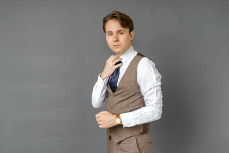 Portrait of a businessman holding his tie with his hand. Gray background. Business and finance conceptの写真素材