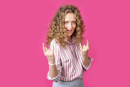 Close up photo of beautiful astonished lady fingers show V-sign toothy beaming smile. Isolated pink backgroundの写真素材