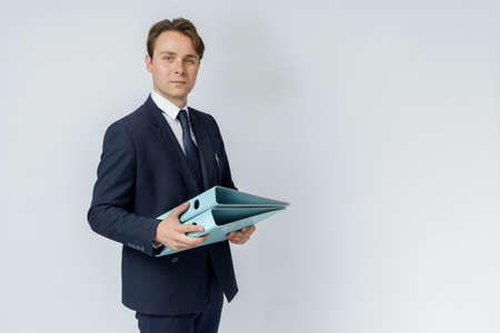 A businessman in a blue suit holds folders on a white background. Business and finance conceptの写真素材