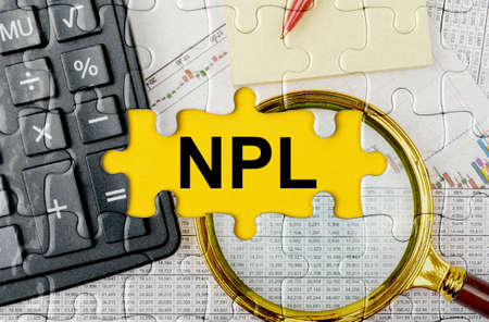 Business concept. Puzzle with a calculator, magnifying glasses and financial documents in the center inscription -NPLの写真素材