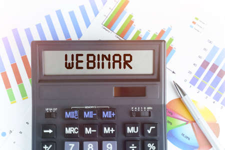 The concept of business and finance. On the table are financial charts and a calculator, on the electronic board of which is written the text - WEBINARの写真素材