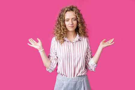 Portrait of a woman who holds her hands up, palms up. Isolated on a pink background.の写真素材