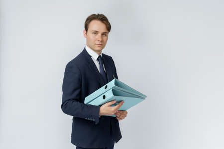 A businessman in a blue suit holds folders on a white background. Business and finance conceptの写真素材