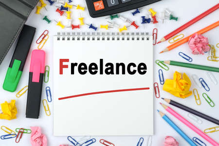 Business concept. On the table is a calculator, diary, markers, pencils and a notebook with the inscription - Freelanceの写真素材
