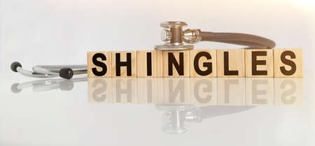SHINGLES the word on wooden cubes, cubes stand on a reflective white surface, on cubes - a stethoscope. Medicine conceptの写真素材