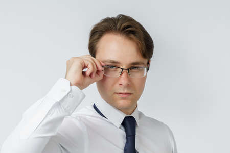 Portrait of a businessman adjusting his glasses. White background. Business and finance conceptの写真素材