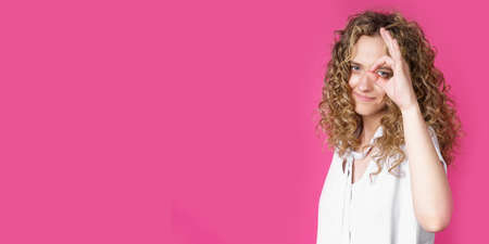 Portrait of a beautiful young woman makes a ok gesture, demonstrates agreement, loves an idea,...