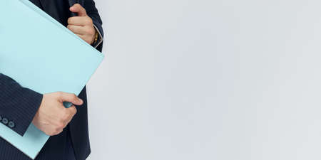 Businessman in a blue suit holds a folder in his hands on a white background. No face visible.の写真素材