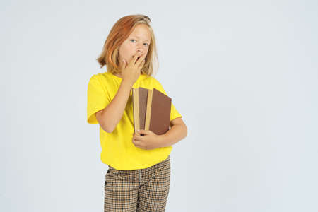 A teenager girl is holding a book in her hands and covers the rock with her hand in surprise. Isolated background. Education concept.の写真素材