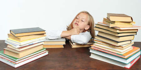 Portrait of a teenage girl who sits at a table among the books and looks to the side. Isolated...
