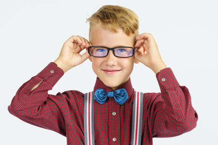 A portrait of a schoolboy adjusting his glasses. Education concept.