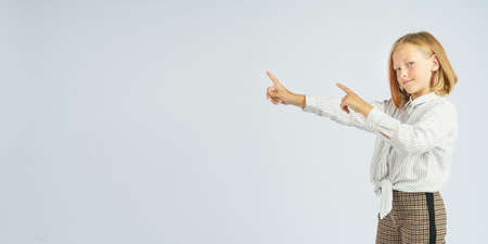 Teenager girl pointing her fingers to the side. Isolated background. Education concept.の写真素材