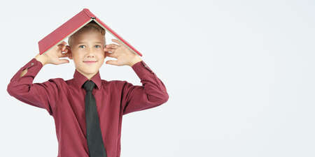 The schoolboy put an open book on his head and covered his ears with his fingers, isolated...