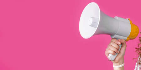 The girl's hand holds a yellow megaphone. Isolated on a pink background.