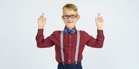 A portrait of a schoolboy who raised his hands up - fingers are twisted together. Isolated...
