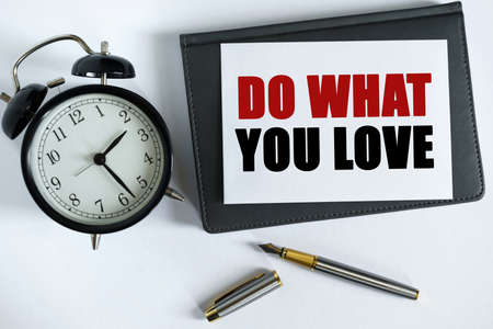 Business and positive concept. On the table there is a clock, a pen, a notebook and a card on which...