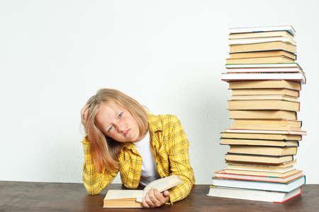 Education concept. A teenage girl is sitting at a table and reading a book.