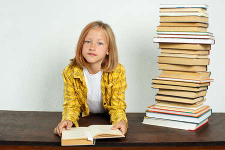Education concept. A teenage girl is sitting at a table and reading a book.