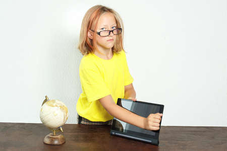 Education concept. The student wipes the tablet screen with her hand. There is a globe on the table