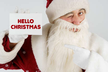 New Year and Christmas concept. Santa Claus holds a card with the text in his hands - HELLO CHRISTMASの写真素材