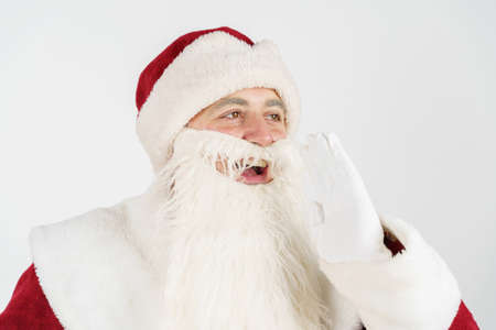 New Year and Christmas concept. Santa Claus put his hand to his mouth and shouts.の写真素材
