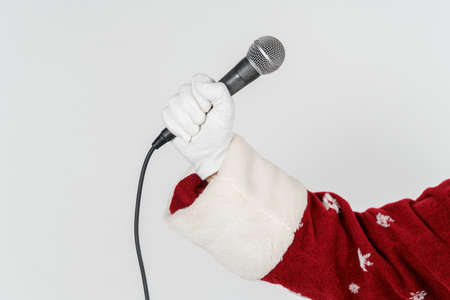 Holidays and Christmas concept. The hand of Santa Claus is holding a microphone in his hand. Isolated on whiteの写真素材