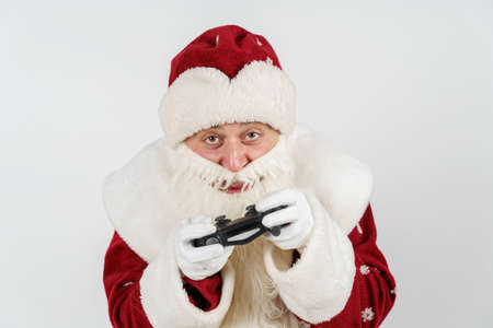 Holidays and Christmas concept. Santa Claus holds a joystick in his hands - he plays a computer...