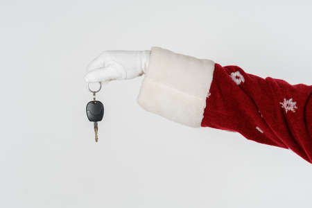 New Year and Christmas concept. Santa Claus is holding a gift - car keys. Isolated on light backgroundの写真素材