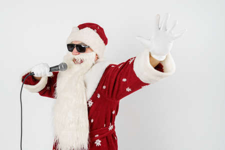 Holidays and christmas concept. Santa Claus sings with a microphone in his hand. Isolated on whiteの写真素材