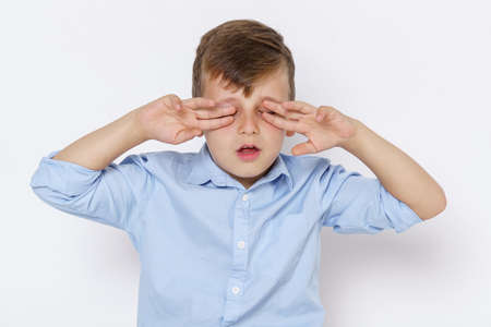 The emotions of a teenager. Portrait of a boy, covering his eyes with his hands. Isolated on white...
